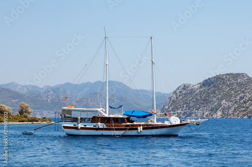 White yacht with wooden deck in the blue sea surrounded by islands on tourism vacation