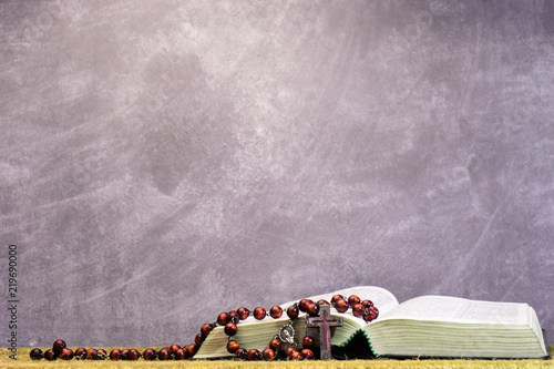 Bible and the crucifix beads on a golden table. Beautiful background. Religion concept photo