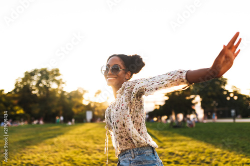 Beautiful smiling african girl in sunglasses joyfully spending time in city park isolated photo