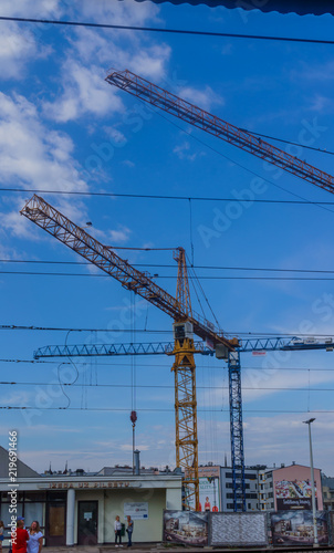 An image of two construction cranes silhouetted against a sky on a city centre building site