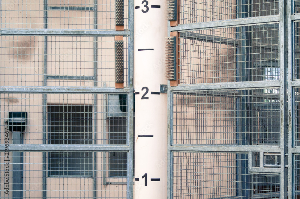Industrial metal fencing with tall pole with numbers in the middle