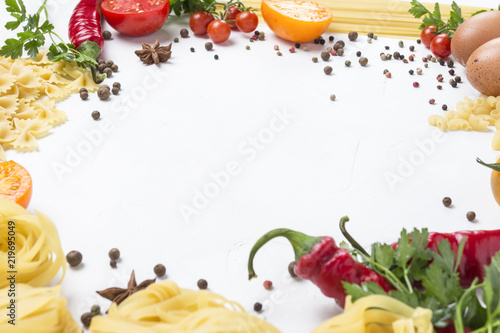 Italian pasta of different kinds with spices, red hot pepper, eggs, yellow and red tomatoes on a white stone background. Concept cooking Italian pasta and sauce. Flat lay, top view. circle shape