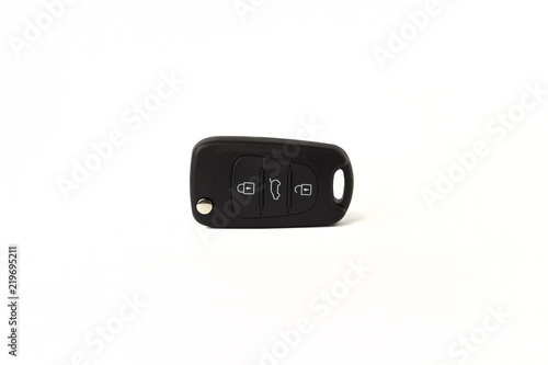 Black key ring with car key with remote control over white background