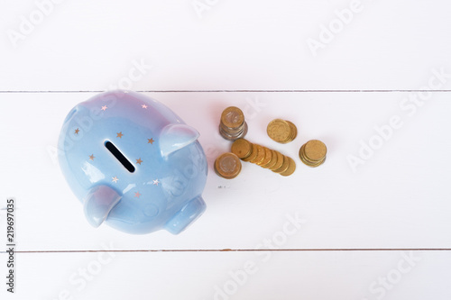 Piggy bank with coins, top view on white wooden background, savings concept