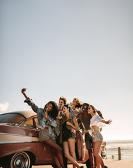 Multi ethnic friends taking a selfie near the car