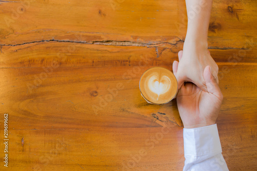 hands of couple drinking coffee at cafe together ,heart shape latte art in coffee cup.
