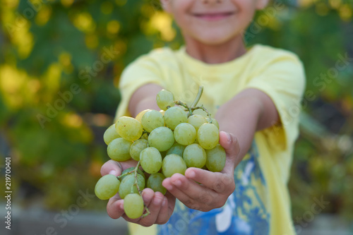 the boy is holding the grapes