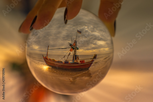 Photography using a crystal ball, showing a small fishing boat on a beach.