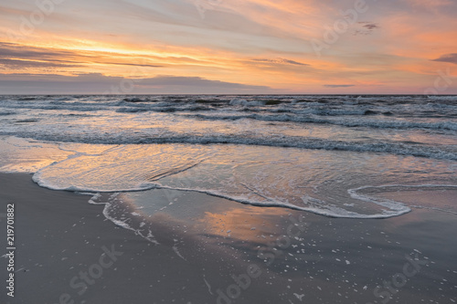 Sunset on Baltic Sea white pastel color sky and rough sea. 