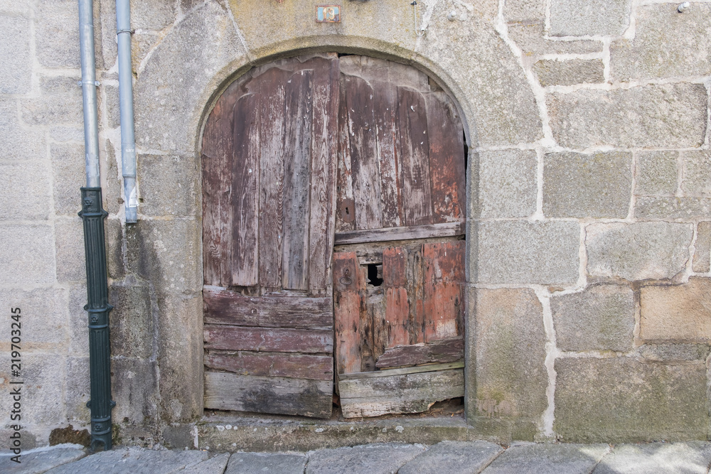 Puerta de arco antigua de madera en casa de piedra de estilo medieval