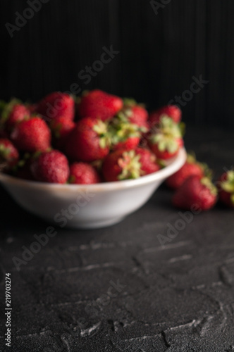 Fresh strawberries in a plate on a black background.