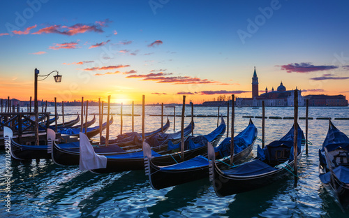 Venice with famous gondolas at sunrise, Italy. Gondolas in lagoon of Venice on sunrise, Italy. Venice with gondolas on Grand Canal against San Giorgio Maggiore church. © daliu