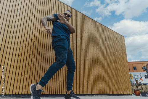 Young man with blue dreadlocks dancing reggaeton in the street.