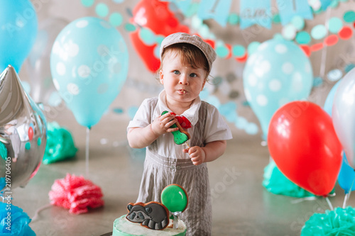 Adorable happy baby boy eating cake one at his first birthday cakesmash party photo