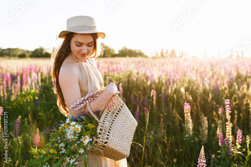 beautiful girl is picking flowers on the spring wildflower field. Horizontal portrait