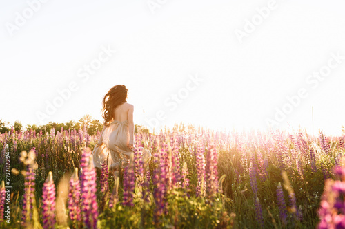 Young woman walking in the field toward the sun. Runaway problems, freedom concept.
