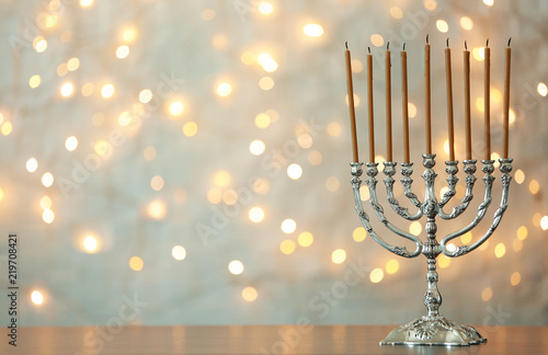 Hanukkah menorah with candles on table against blurred lights