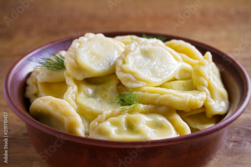 Dumplings, filled with cheese - vegetarian dish. Varenyky, vareniki, pierogi, pyrohy in a bowl on wooden table. horizontal