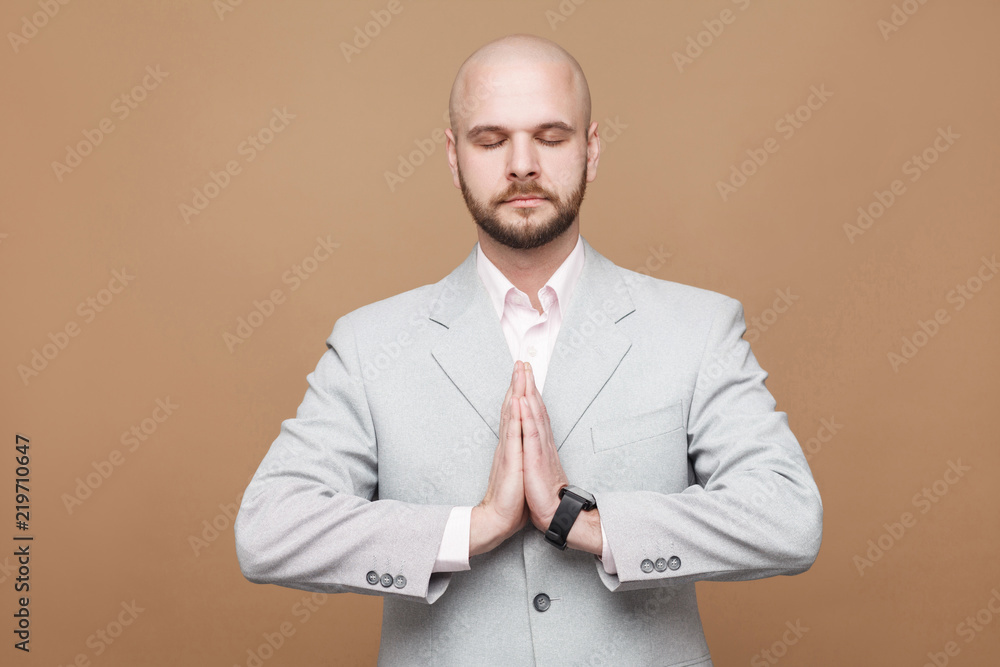 Pointing finger and amazed portrait of handsome middle aged businessman in classic light gray suit standing, looking at camera, wondering and showing brown background. indoor studio shot, isolated. Pointing finger and amazed portrait of handsome middle aged businessman in classic light gray suit standing, looking at camera, wondering and showing brown background. indoor studio shot, isolated.