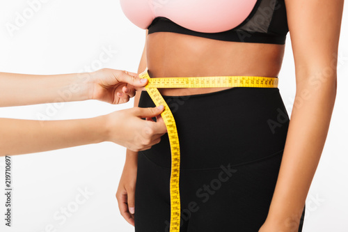 Close up hands measuring woman waist over white background isolated. Plus size model