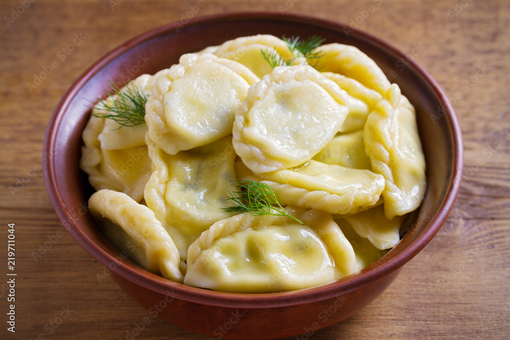 Dumplings, filled with cheese - vegetarian dish. Varenyky, vareniki, pierogi, pyrohy in a bowl on wooden table. horizontal Dumplings, filled with cheese - vegetarian dish. Varenyky, vareniki, pierogi, pyrohy in a bowl on wooden table. horizontal