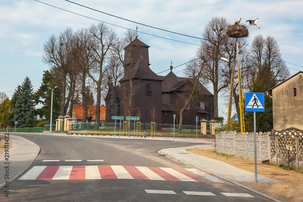 Rural village with wooden church and stork on lamp, Greater Poland province