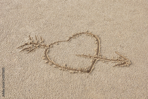 heart pierced by an arrow drawing on the sand beach