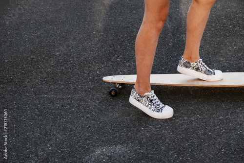 Close up of girl skateboarder feet while skating in the park on asphalt surface