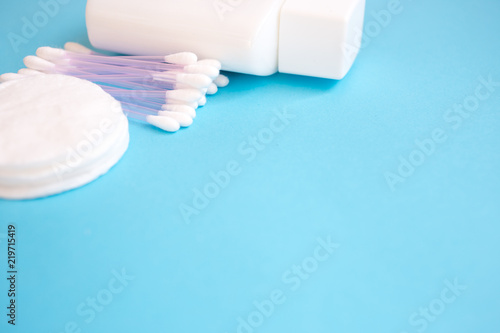 top view personal care products. white bottle, razor, ear sticks, cotton pads, toothbrush on blue background. copy space