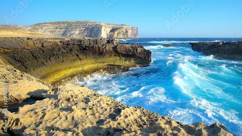 The foamy azure waves of Mediterranean sea crash against the small rocky haven on San Lawrenz coast, next to Dwejra Window site, Gozo Island, Malta. photo