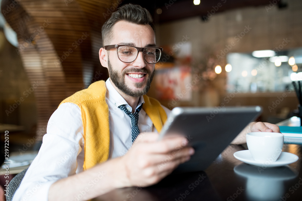 Portrait of cheerful modern businessman using digital tablet sitting at bar counter in cafe Portrait of cheerful modern businessman using digital tablet sitting at bar counter in cafe
