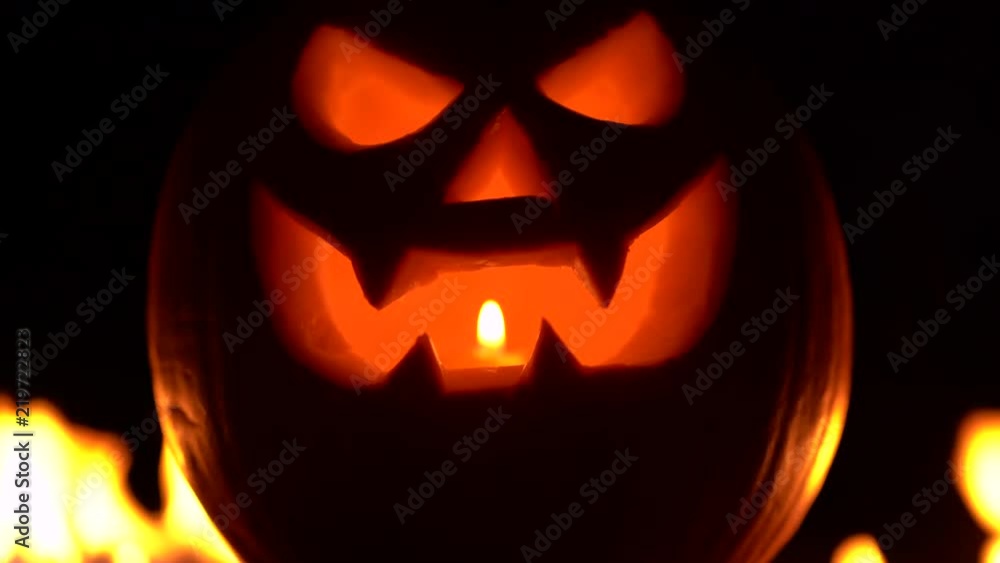 Awful carved halloween pumpkin against of fiery explosion background. Glowing face trick or treat. Symbol of All Hallows' Eve or All Saints' Eve. 4k Awful carved halloween pumpkin against of fiery explosion background. Glowing face trick or treat. Symbol of All Hallows' Eve or All Saints' Eve. 4k