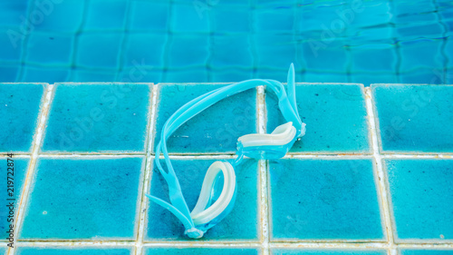 .Glasses on blue tile floor swimming pool close up