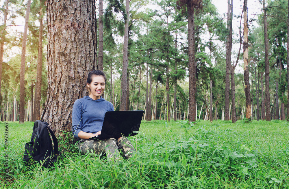Woman use laptop computer in outdoor.Asian girl relaxing on the grass in her spring road trip, carefree and enjoying freedom and travel. Woman use laptop computer in outdoor.Asian girl relaxing on the grass in her spring road trip, carefree and enjoying freedom and travel.