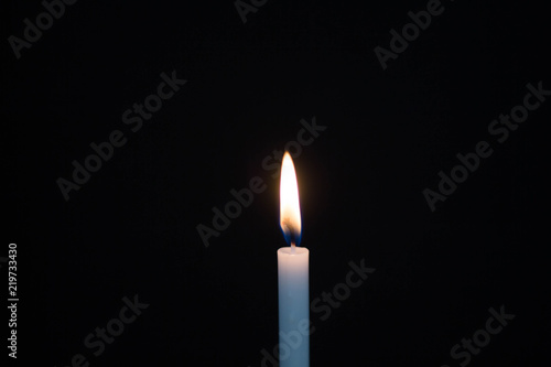 One light candle burning brightly on black background