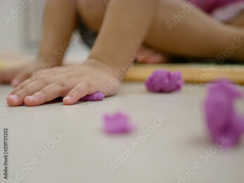 Selective focus of little baby's hands playing play dough on the floor at home