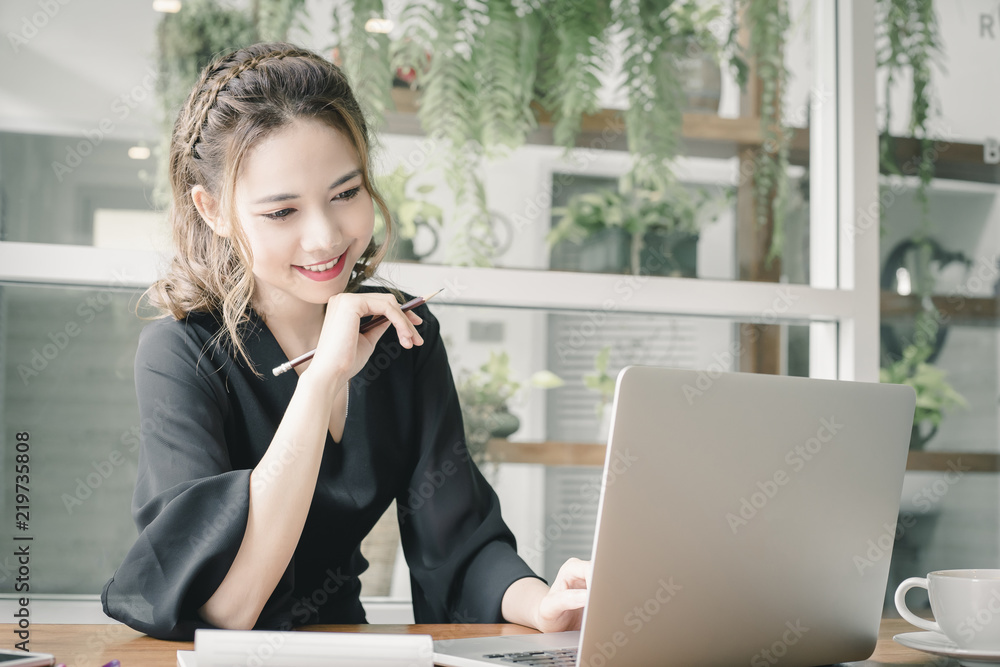 Confident happiness young woman working on laptop or notebook in her office. Beautiful Freelancer Woman working online at her home. Beauty Asian business woman concept.
