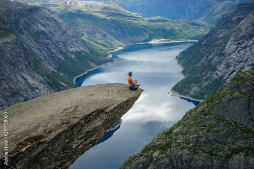 Yog is praying on the edge Trolltunga. Norway. concept of peace, goodness and serenity