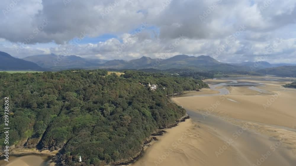 Aerial view, down move. Drone panorama over low tide sea and sand. Lighthouse next to Porthmeirion in Wales Aerial view, down move. Drone panorama over low tide sea and sand. Lighthouse next to Porthmeirion in Wales