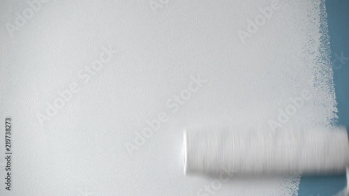Roller painting blue wall with white paint
