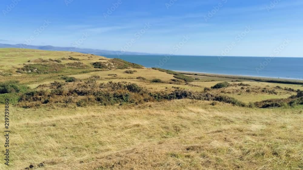 tilt up move. Panorama of dry grass fields, beach and sea in Wales tilt up move. Panorama of dry grass fields, beach and sea in Wales