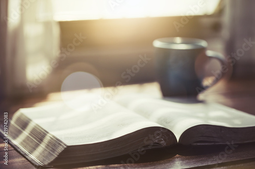 open bible  book with a cup of coffee against window light in the morning, christian devotional