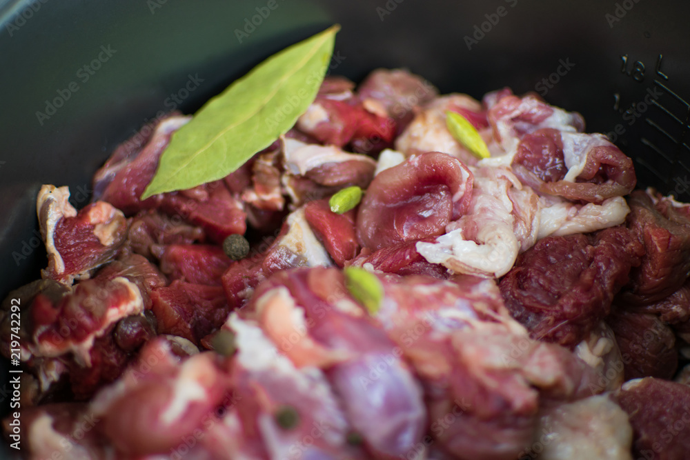 Raw pork chop with spices in a dark saucepan.