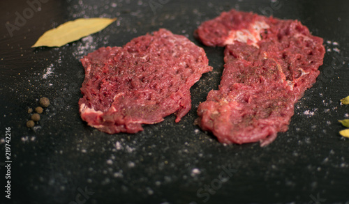 Raw pork chop with spices on a dark background.