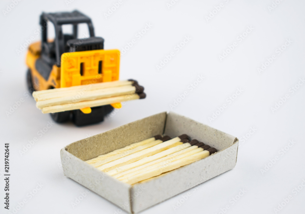 forklift truck with with matches loads into a matchbox on a light background. forklift truck with with matches loads into a matchbox on a light background.