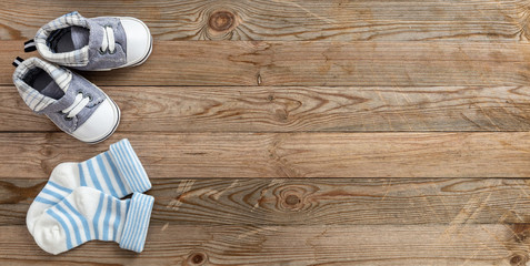 Baby boy shoes and socks on wooden background