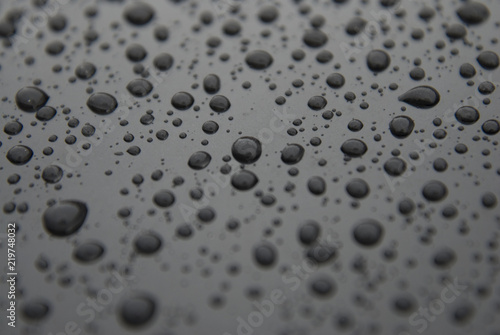 Water rain drops bakground over black surface texture. Beautiful texture of rain drops.