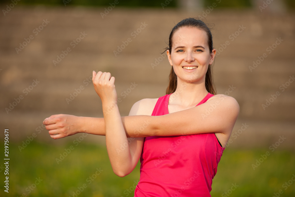 Woman stretch arms on athletic track Woman stretch arms on athletic track