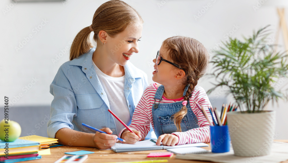 mother and child daughter doing homework writing and reading at home. mother and child daughter doing homework writing and reading at home.