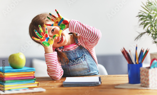 Fotografia funny child girl draws laughing shows hands dirty with paint